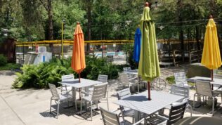 patio seating with umbrellas next to a gated pool at Elkhart RV Resort