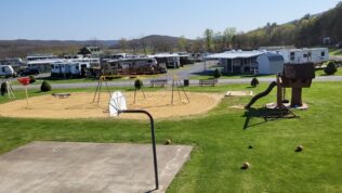 A basketball court, playground, jungle gym, and rv parking at James Creek RV Resort