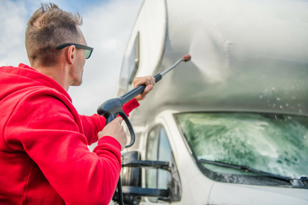 Man powerwashing RV after performing external RV maintenance.