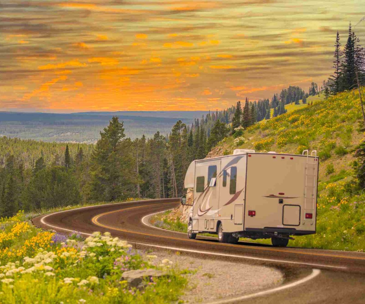 RV driving down a winding highway at sunset.