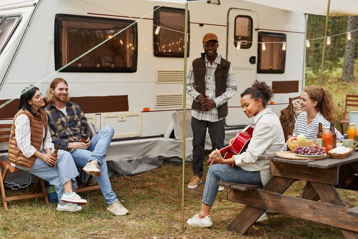 Family and friends gather near their RV for a night of food and music.