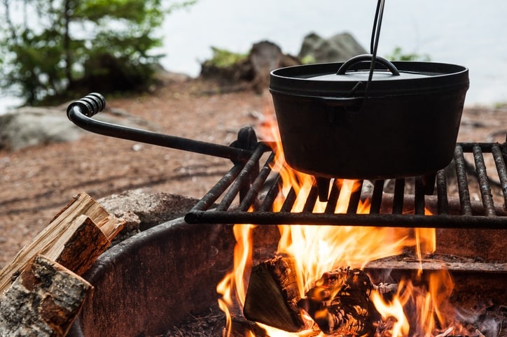 A Dutch oven over a campfire in the woods.