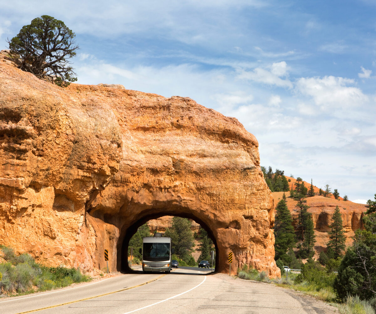 an RV drives through a tunnel in a rock formation
