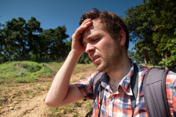 A man experiencing heat exhaustion while out on a hike.