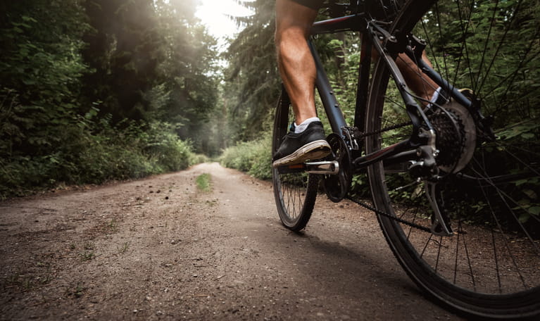 A strong calf pedaling on a bike on a trail.