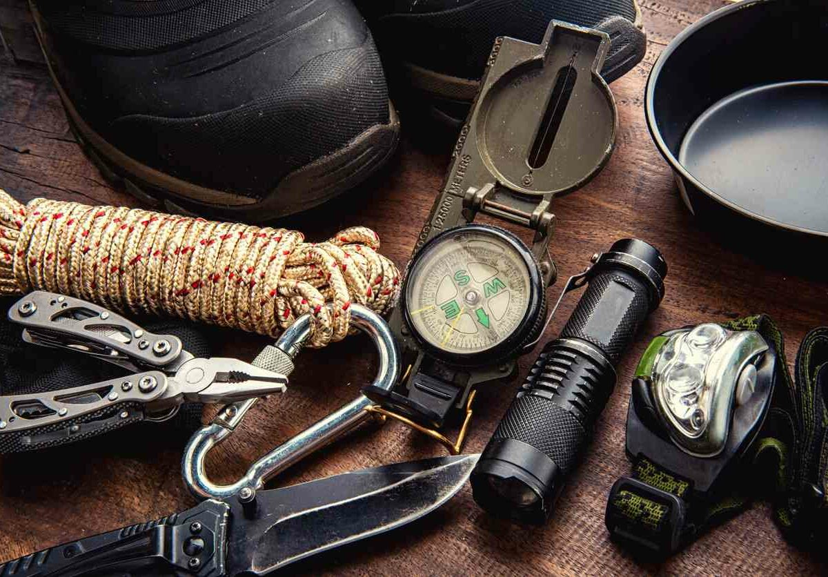 A variety of essential camping equipment is laid out on a table