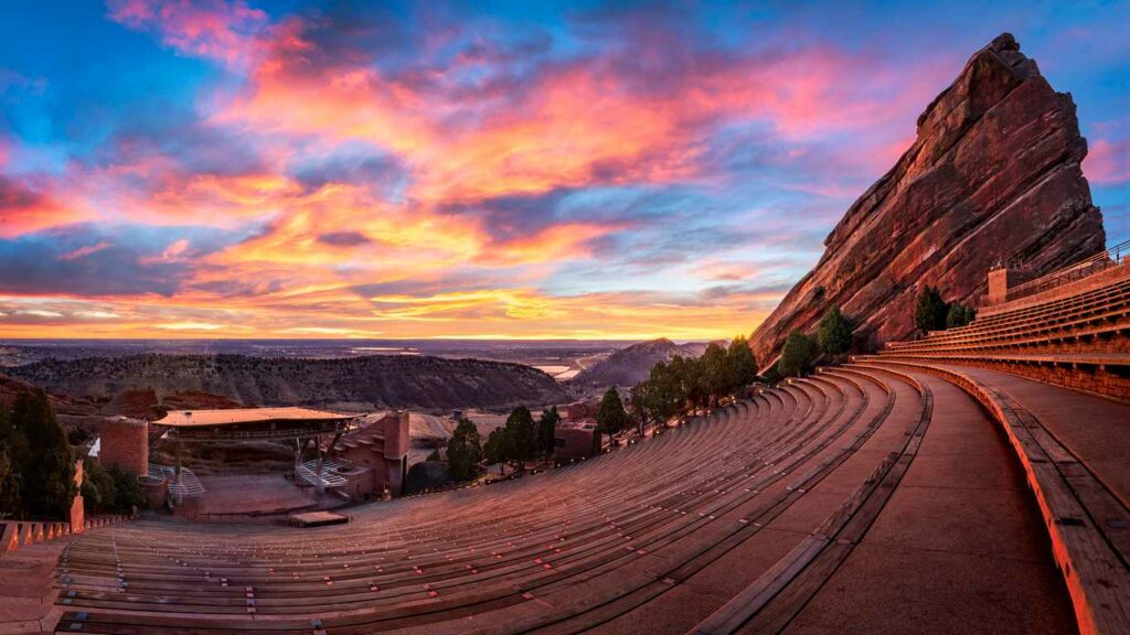 A view looking over Red Rocks Amphitheatre with a sunset and clouds in the background