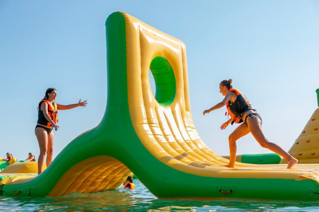 Two kids play on a floating inflatable aqua park