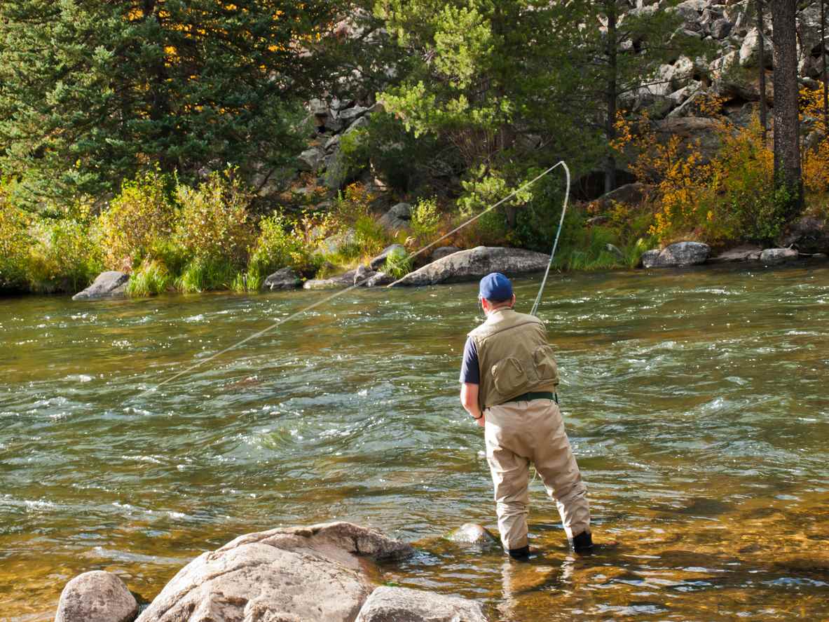 A person fly-fishing along a Colorado river.