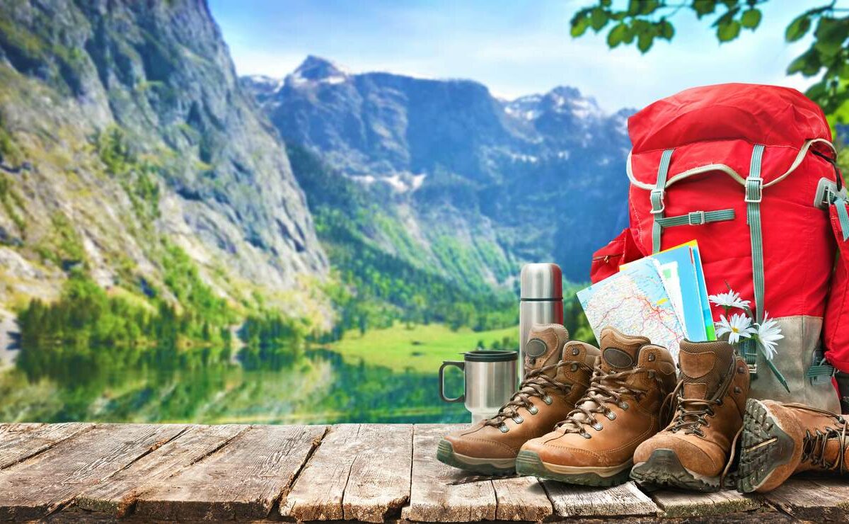 Hiking gear on a wooden table in front of a lake landscape.