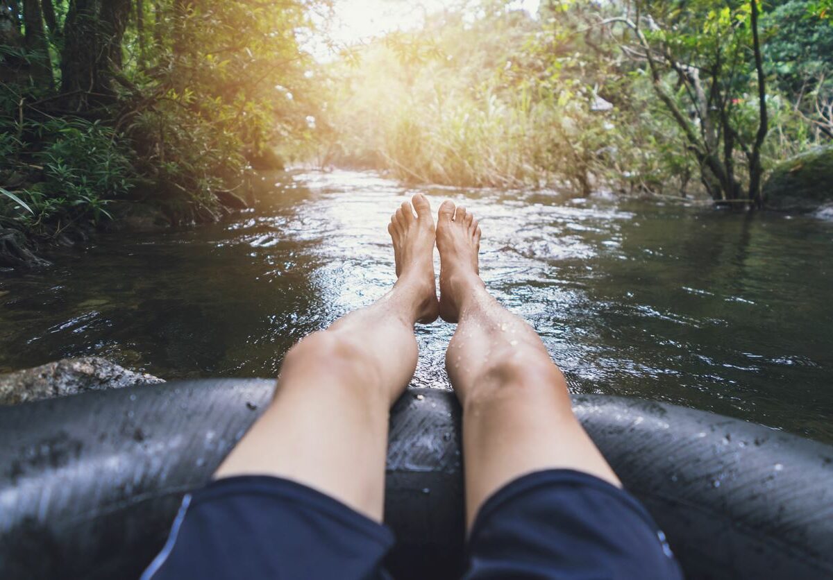 First-person perspective of a man floating down a river on a tube.