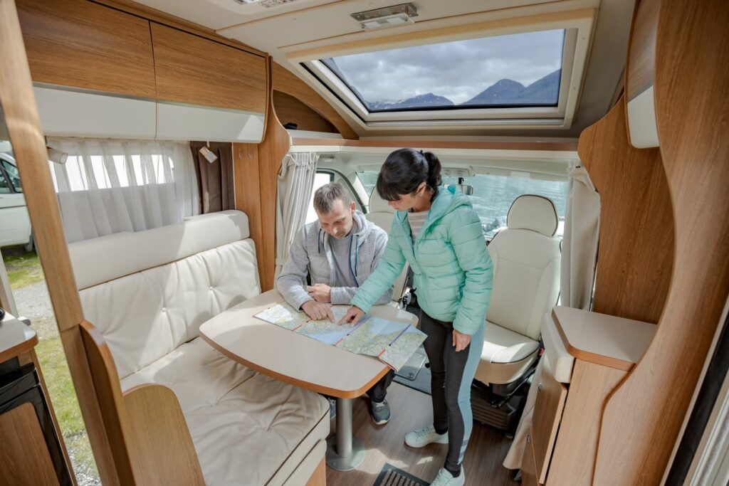 A couple sitting inside their RV planning out their route with a map.