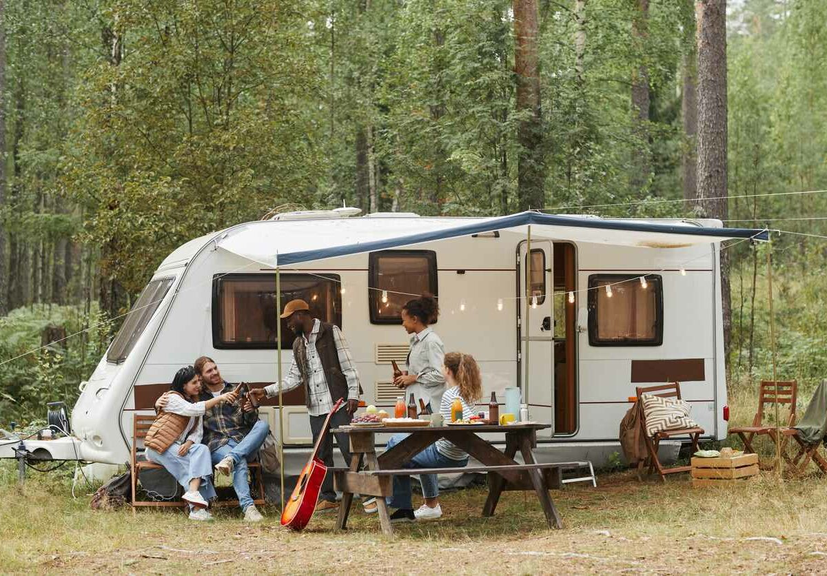 Shot of a group of friends relaxing by an RV in a campground.