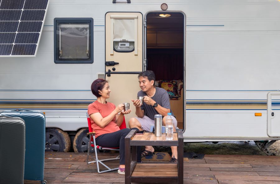 A couple seated at a small wooden table enjoying their time together while RV camping.