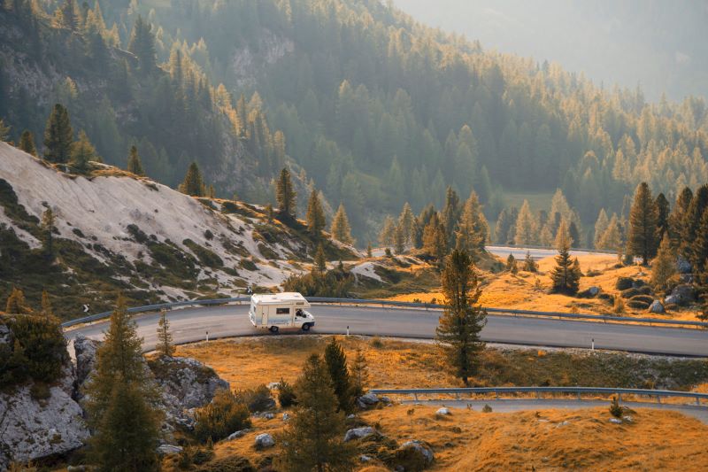 An RV driving down a scenic highway along a mountainside.