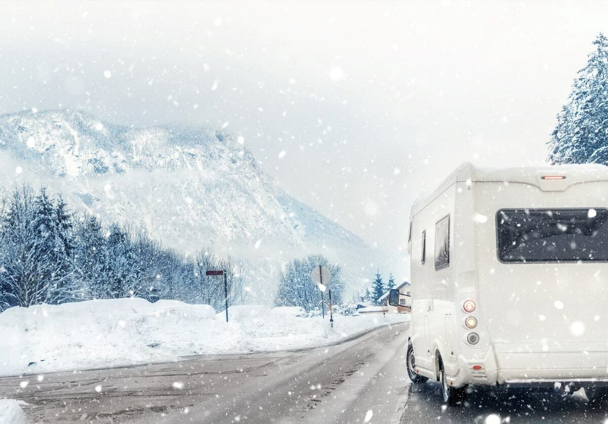 An RV driving down a snowy road on its way to a camping trip.