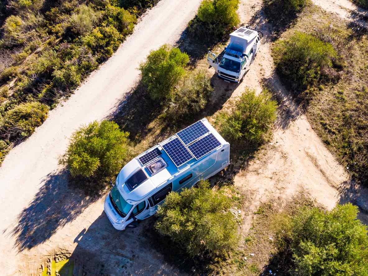 Eco-friendly RVs with solar panels on the roof driving on dirt roads.