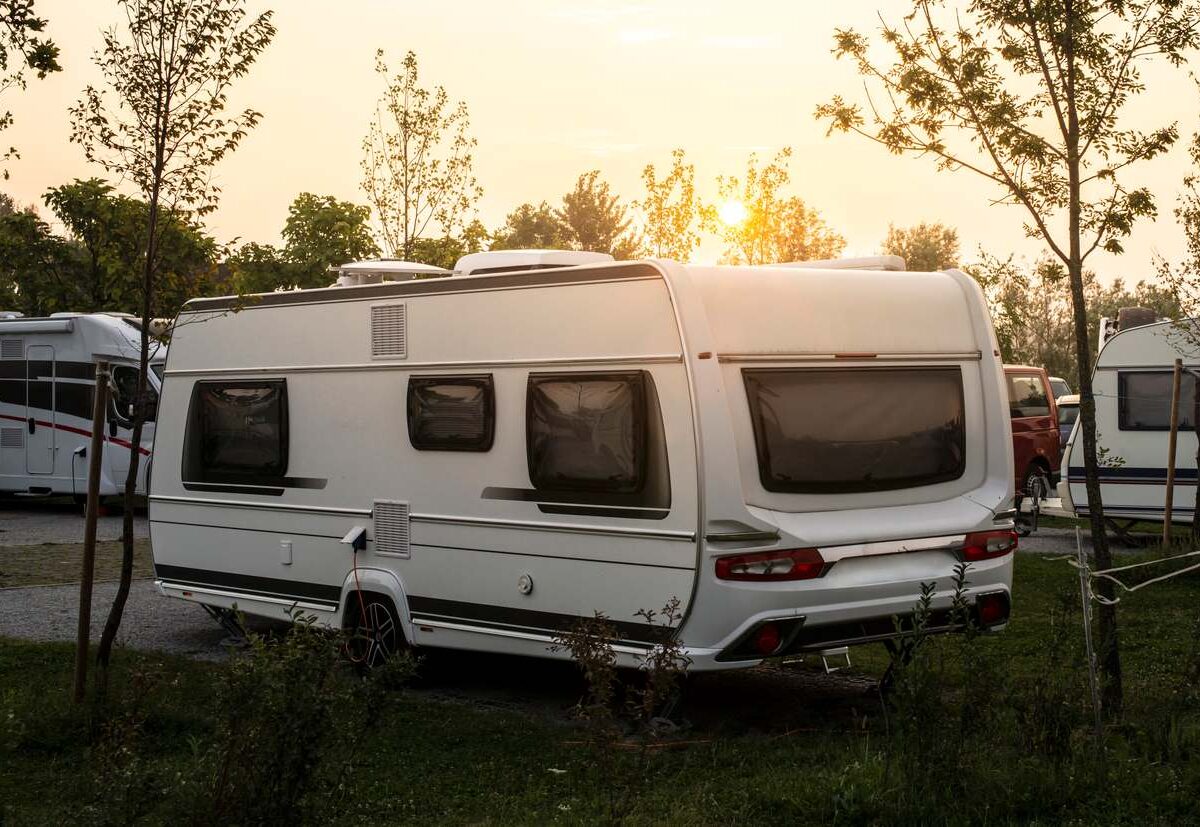 Camper parked on the green meadow for long-term RV camping.