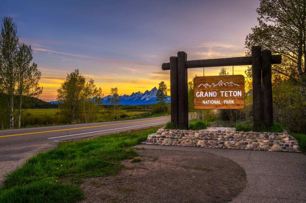 Welcome sign at the entrance of Grand Teton National Park in Wyoming with the sun setting behind.