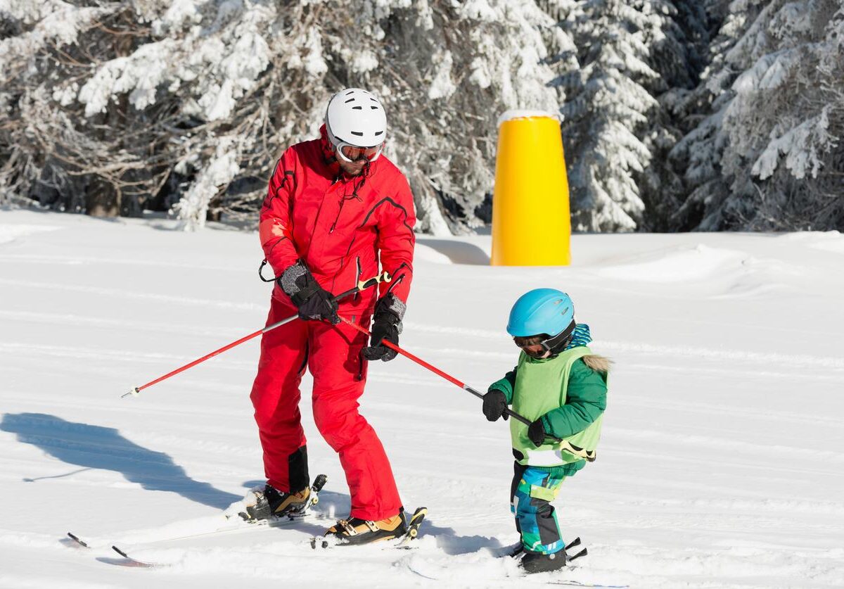 A parent and child wearing full winter gear while skiing.