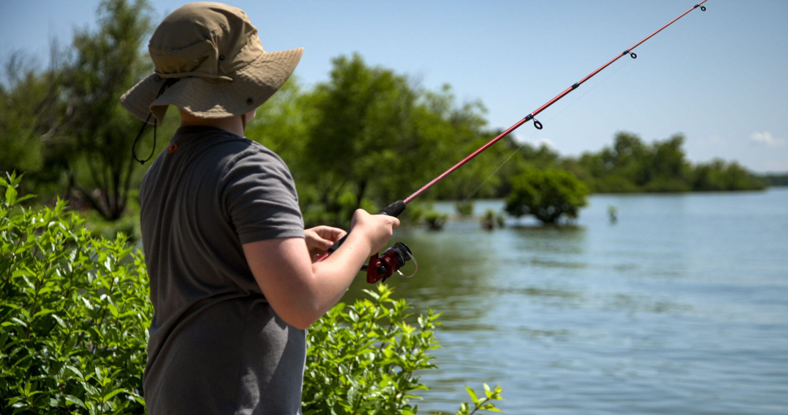 A young man fishing on the shores of Grand Lake O' The Cherokees RV Resort.