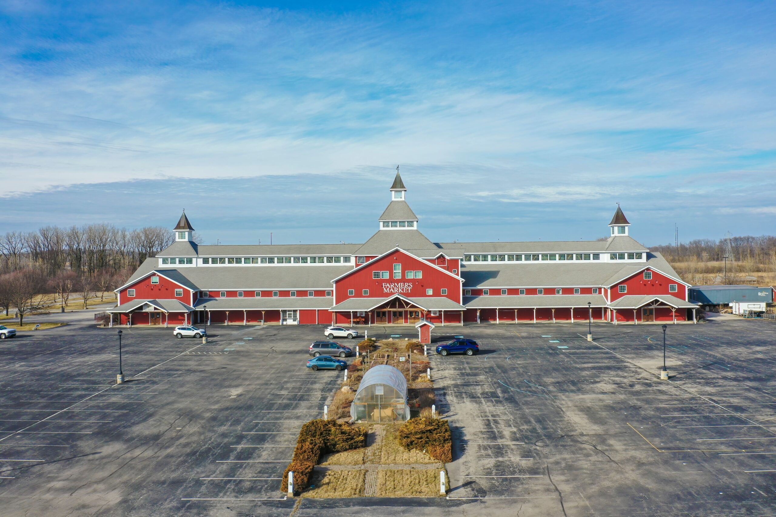 A vast red bustling farmers market amid a lush hillside, bathed in sunlight in Elkhart, Indiana, adds vibrancy to the scene.