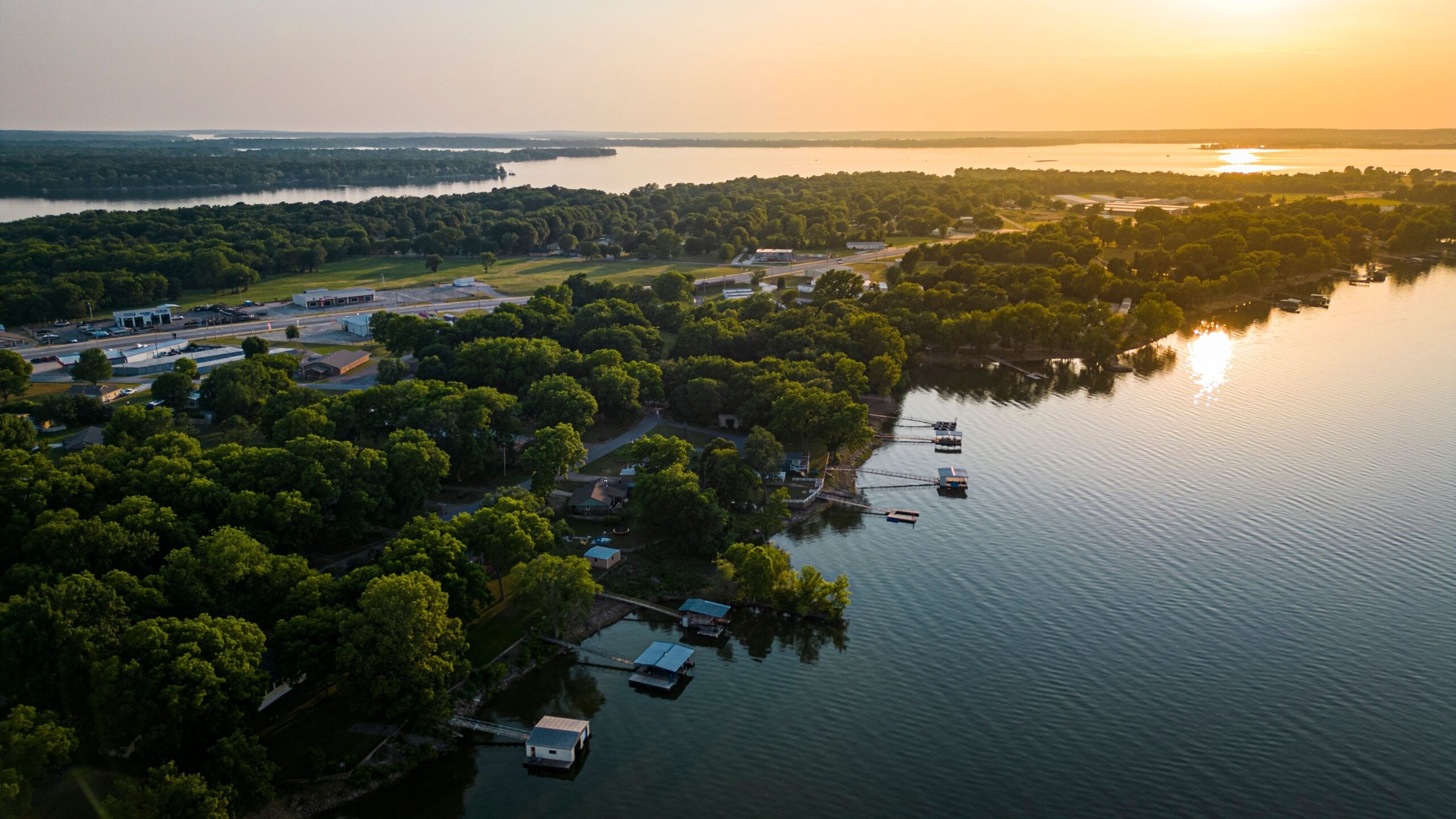 An aerial view of the beautiful Grand Lake Oklahoma at sunset, with the lake's waters reflecting the hues of the setting sun