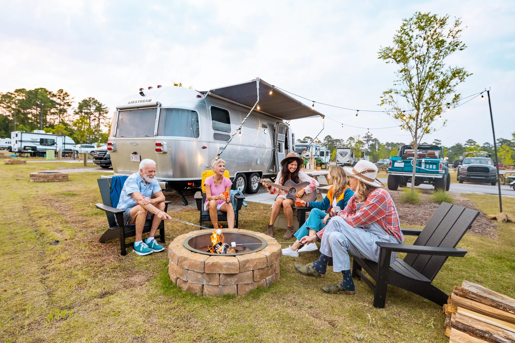 A group of happy campers roast marshmallows around a nice campfire in a fire ring at an RJourney RV Resort