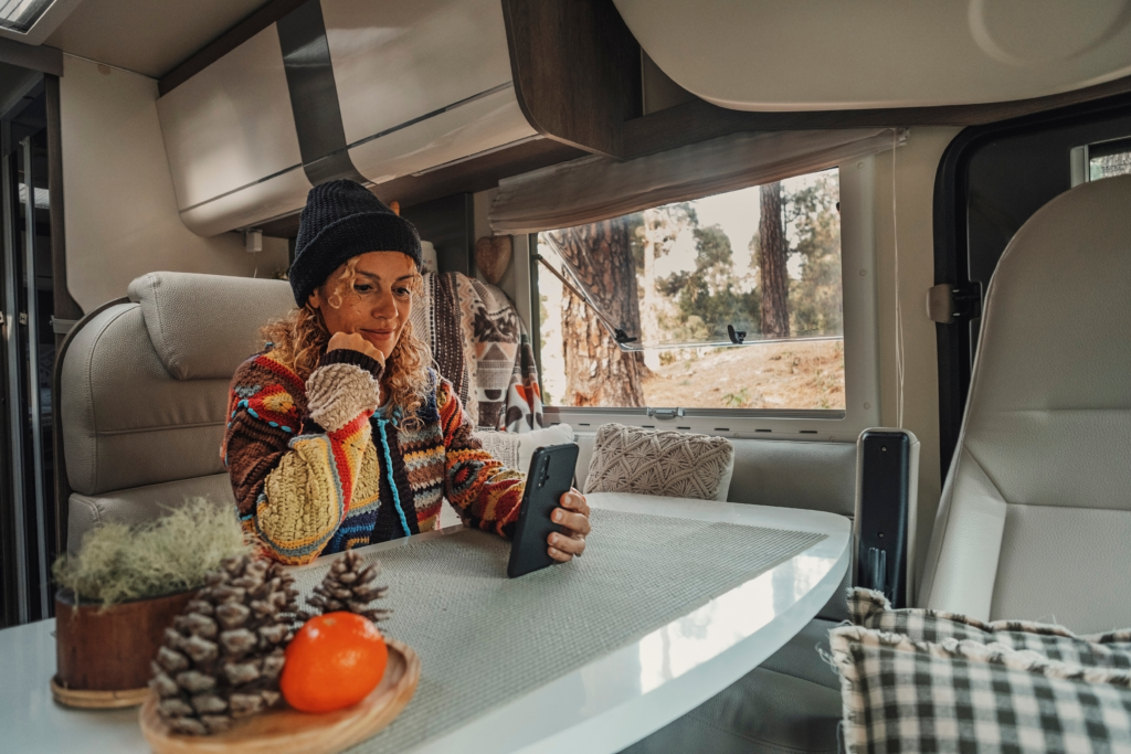 A woman looks at her smart phone at the kitchen table of her RV.
