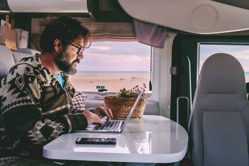 A man in an RV works on his Laptop doing remote work.