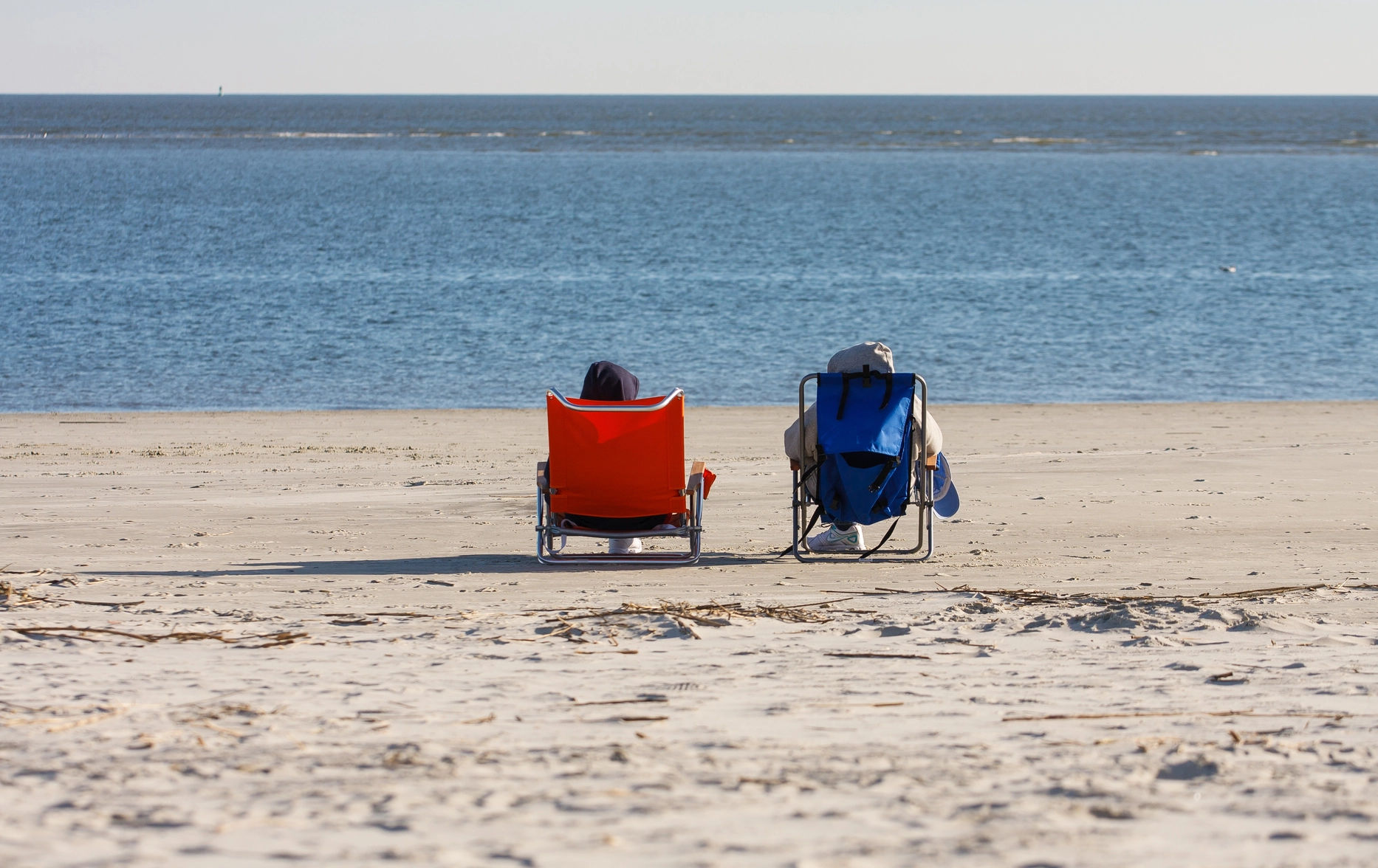 Two people resting in orange and blue beach chairs