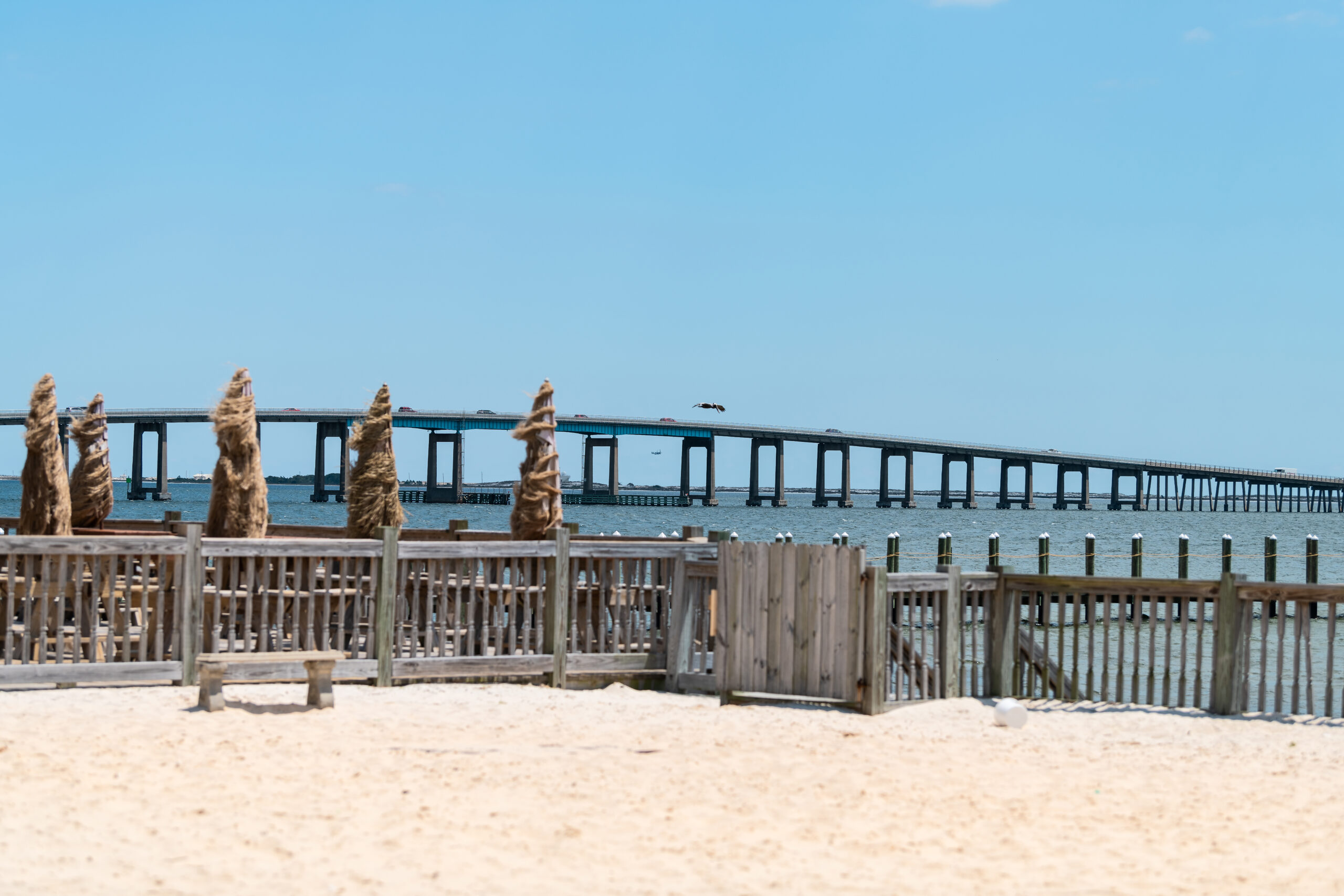 Florida Panhandle Beach with abandoned pier and a bridge in the background.