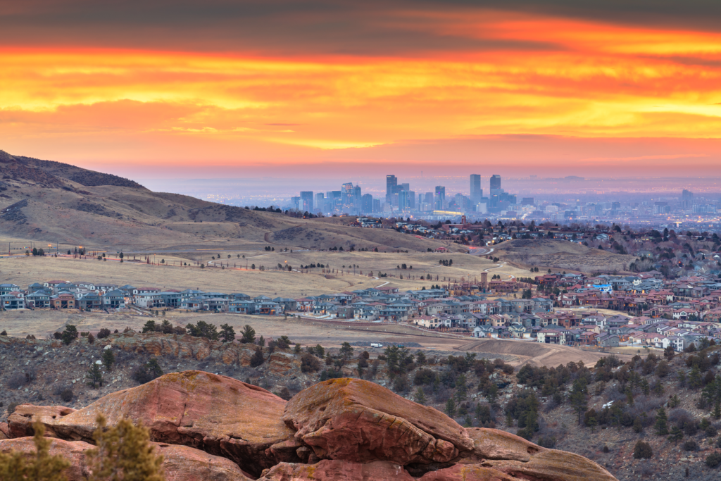A view of the sunset with the Denver skyline on the horizon and beautiful wilderness in the foreground.