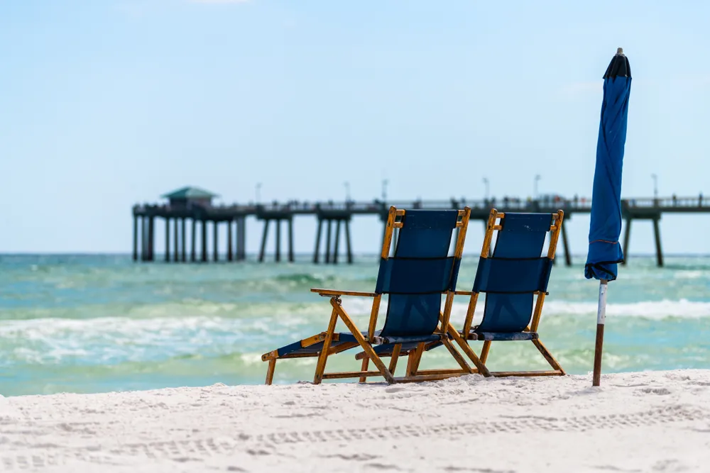 Blue beach chairs and a fishing pier on the white sand Gulf Coast near Milton, Florida